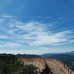A breathtaking view of the Great Wall of China stretching across lush mountains under a vibrant blue sky.