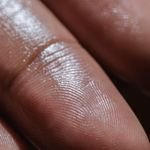 لقطة ماكرو مقرّبة لطرف إصبع رطب تُظهر خطوط بصمة الجلد وتفاصيل نسيجه ولمعان الماء عليه